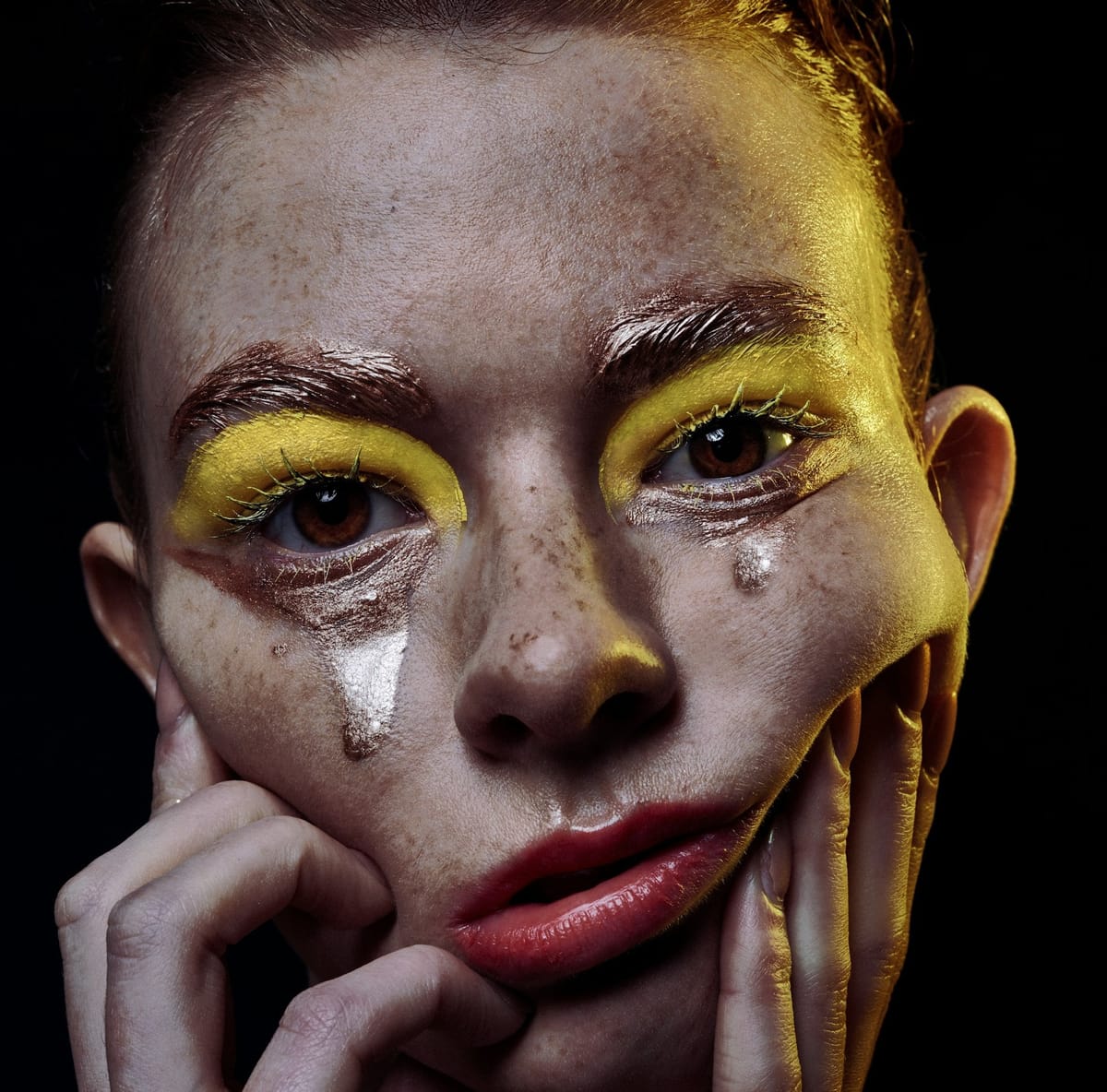 A young person wearing simple clown makeup with tears marring the effect